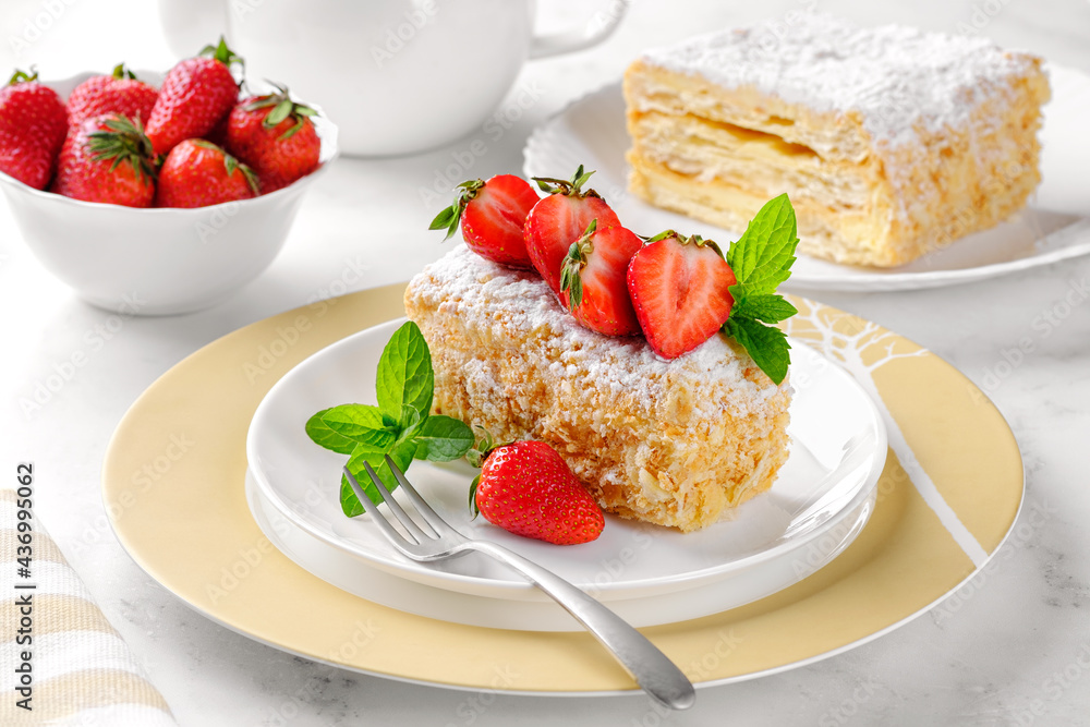 A slice of Napoleon cake with strawberries and mint. Russian cuisine, layer cake with cream, close up. A slice of Napoleon cake with strawberries and mint. Russian cuisine, layer cake with cream, close up.
