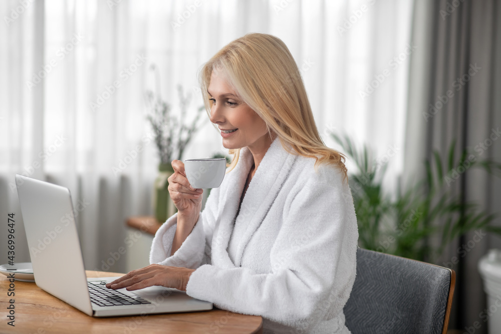 Pretty blonde woman sitting at the laptop and looking thoughtful Pretty blonde woman sitting at the laptop and looking thoughtful