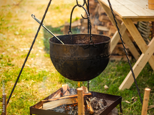Cooking street food. Cooking soup in a cauldron on a fire outside.