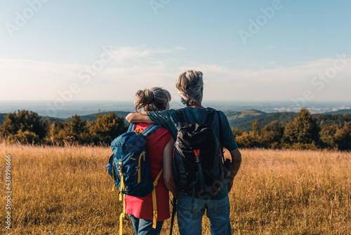 Active senior couple hiking in nature with backpacks  enjoying their adventure at sunset.