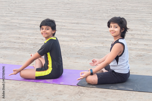 Two boys practicing yoga at beach
