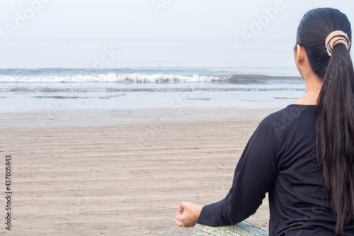 Rear view of woman meditating at the beach