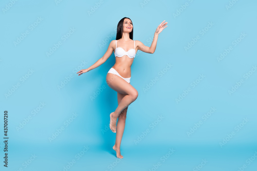Full body photo of positive brown hairdo lady look empty space wear white lingerie isolated on blue background Full body photo of positive brown hairdo lady look empty space wear white lingerie isolated on blue background