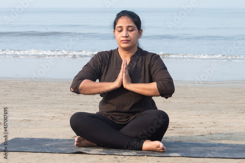 Woman meditating in prayer pose at seafront