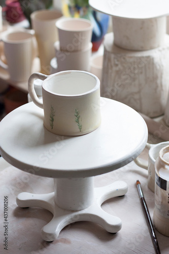 A ceramic mug stands on the turnstile. Ceramist's Workshop