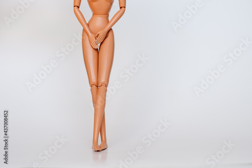 Nude doll covering pelvic area white background