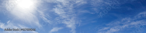 Blue sky with a sun and light beautiful white clouds, panoramic photo.