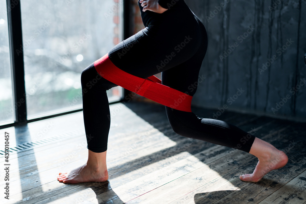 Photo of female legs in black leggings doing exercises in the gym using an elastic band Photo of female legs in black leggings doing exercises in the gym using an elastic band