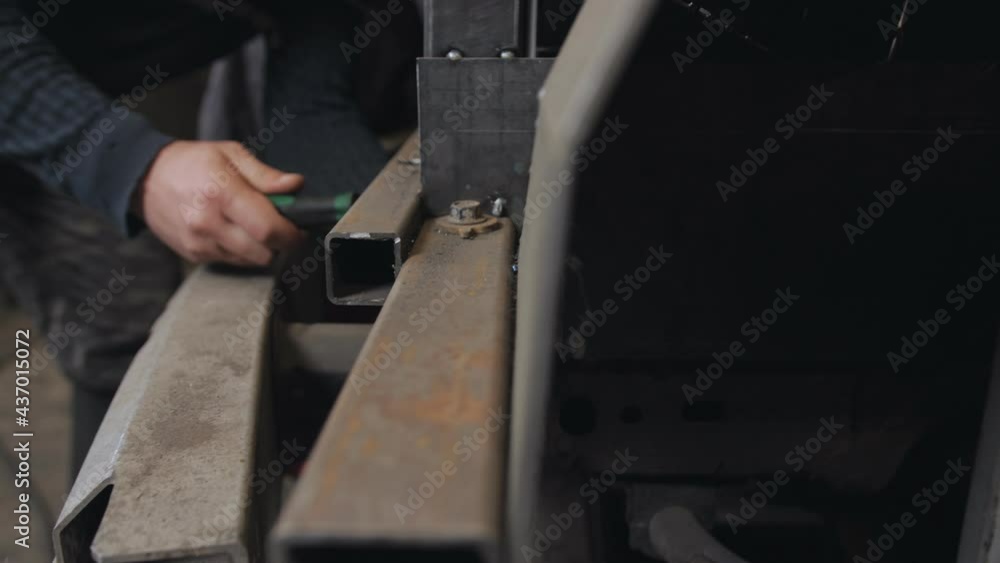 Close-up of a mechanic's hands tightening a bolt in a metal frame with a screwdriver. Close-up of a mechanic's hands tightening a bolt in a metal frame with a screwdriver.