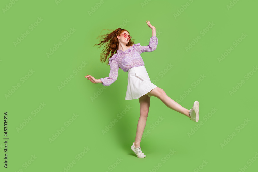 Full length profile photo of cool red hairstyle young lady go wear blouse skirt spectacles isolated on green color background Full length profile photo of cool red hairstyle young lady go wear blouse skirt spectacles isolated on green color background