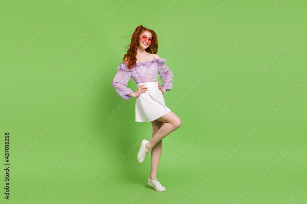 Full size photo of optimistic red hairstyle young lady stand wear blouse skirt spectacles isolated on green color background Full size photo of optimistic red hairstyle young lady stand wear blouse skirt spectacles isolated on green color background