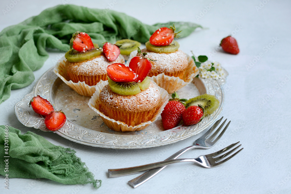 Close-up of delicious muffins with berries on a silver platter on a light background Close-up of delicious muffins with berries on a silver platter on a light background