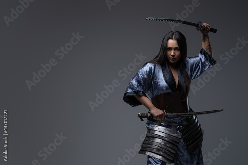 Aggressive woman samurai in fight stance with katanas