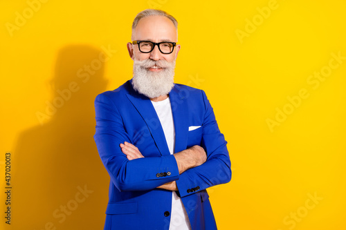 Photo portrait of senior man in blue suit glasses smiling with crossed hands isolated bright yellow color background photo