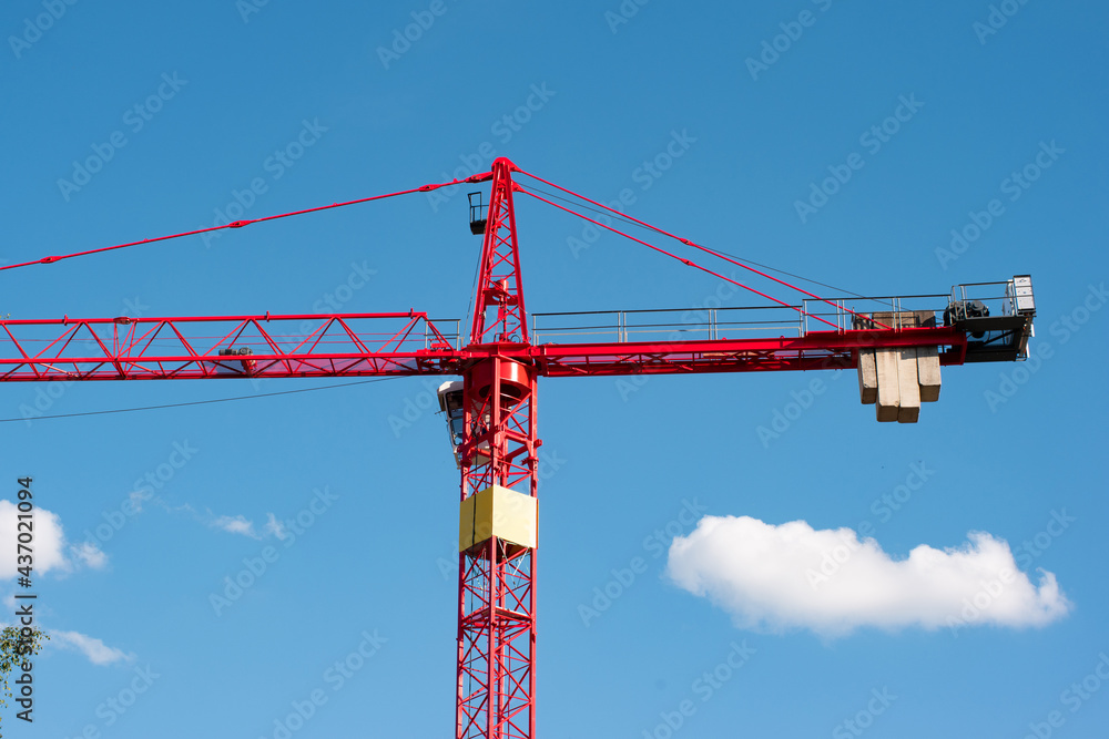 Big red metal construction crane set against blue sky low angle view Big red metal construction crane set against blue sky low angle view