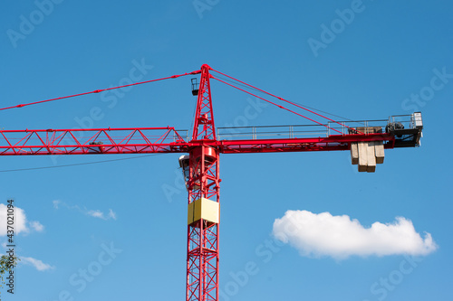 Big red metal construction crane set against blue sky low angle view