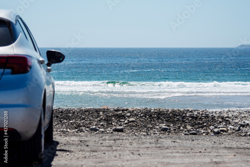 Car parked by the ocean view beautiful view on blue water surface. Warm sunny day. Travel and tourism concept, copy space.