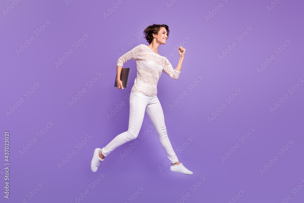 Full length photo of charming young lady dressed white shirt jumping holding modern device isolated purple color background