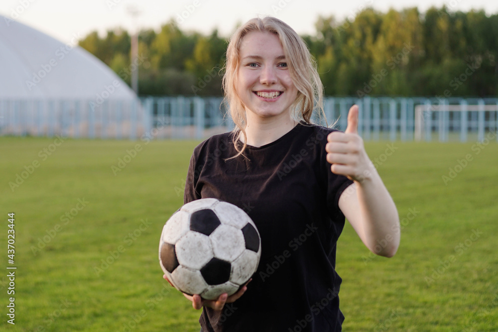 Young teen girl football player holding soccer ball with thumb up Stock