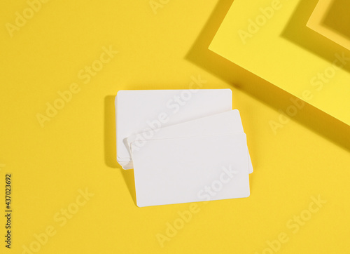 blank white rectangular business card on creative yellow background from sheets of paper with shadow