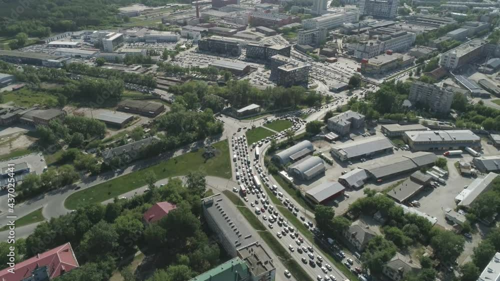 Aerial view of Roundabout road junction in a big city. Traffic jams on the roads. Nearby are residential buildings, industrial zone and office buildings. There are many trees in the city. Sunny summer Aerial view of Roundabout road junction in a big city. Traffic jams on the roads. Nearby are residential buildings, industrial zone and office buildings. There are many trees in the city. Sunny summer