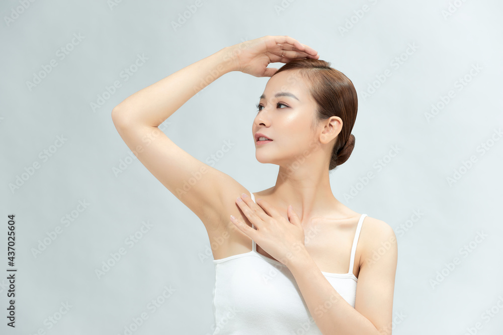 Close-up of a beautiful young woman showing her smooth armpit isolated on white background
