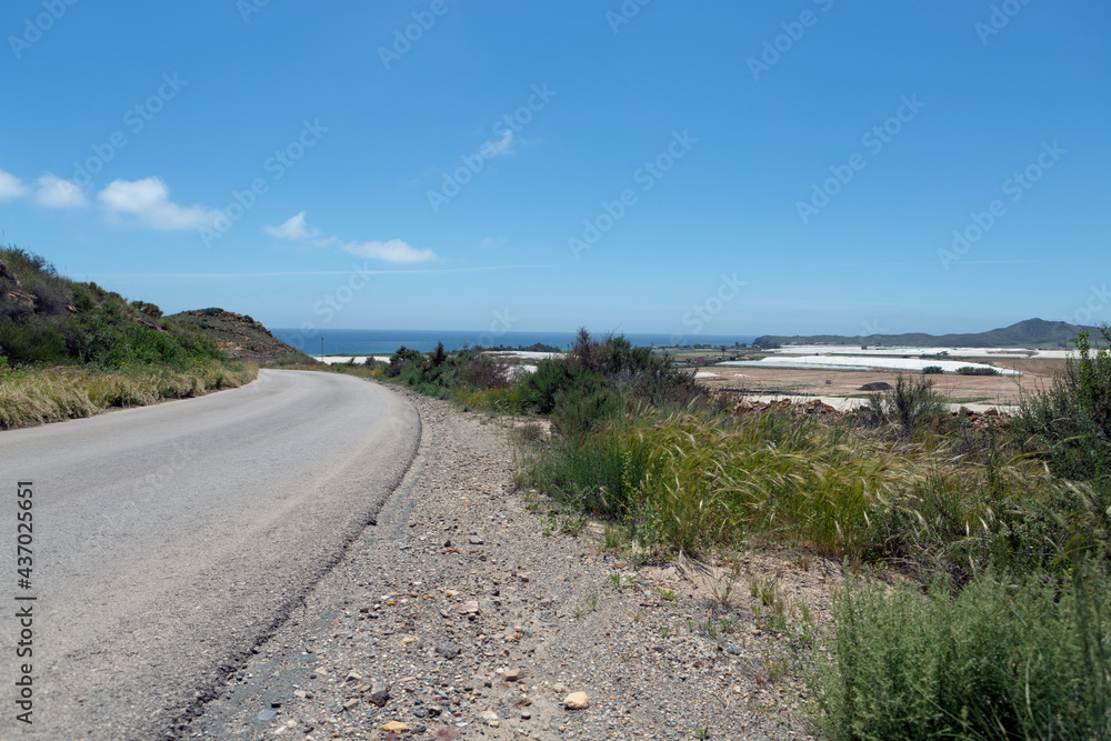 Sharp curve on a secondary road, with a view of the sea front and one side of the greenhouse Sharp curve on a secondary road, with a view of the sea front and one side of the greenhouse