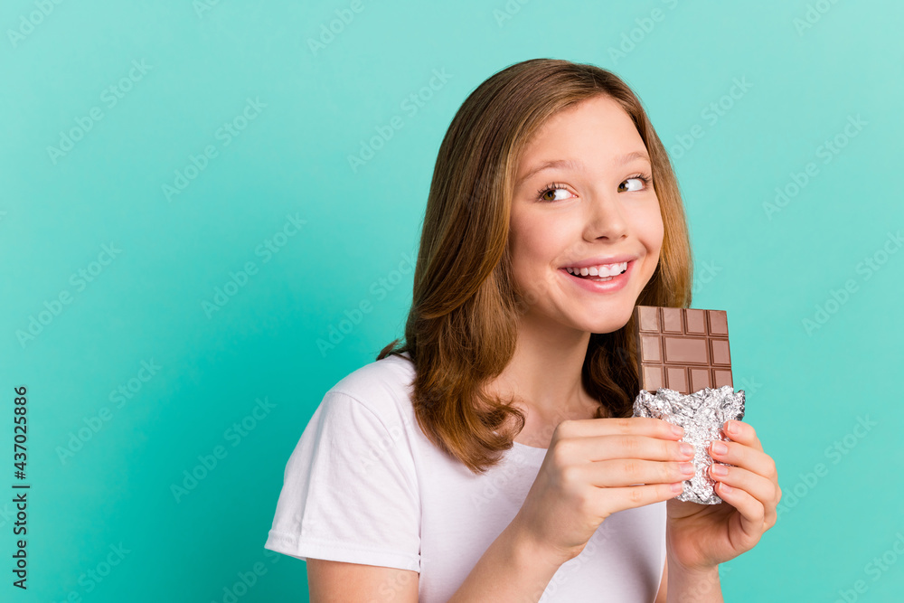 Photo portrait girl smiling happy eating chocolate looking copyspace dreamy enjoying isolated vivid teal color background Photo portrait girl smiling happy eating chocolate looking copyspace dreamy enjoying isolated vivid teal color background