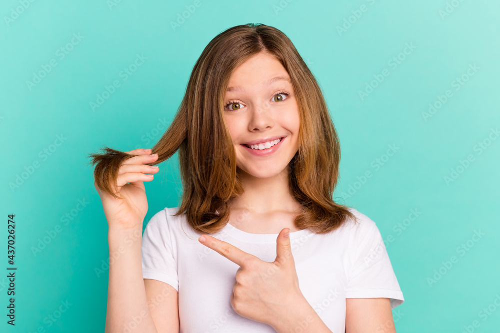 Photo portrait girl showing hair ends pointing finger smiling isolated vibrant teal color background Photo portrait girl showing hair ends pointing finger smiling isolated vibrant teal color background