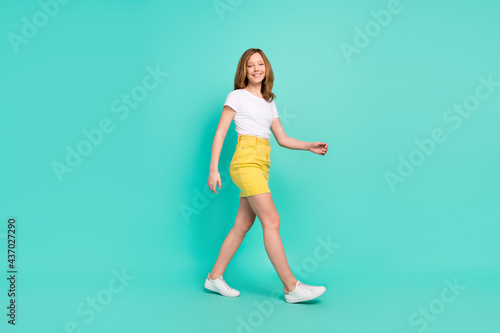 Full length body size photo smiling schoolgirl walking forward isolated vivid teal color background