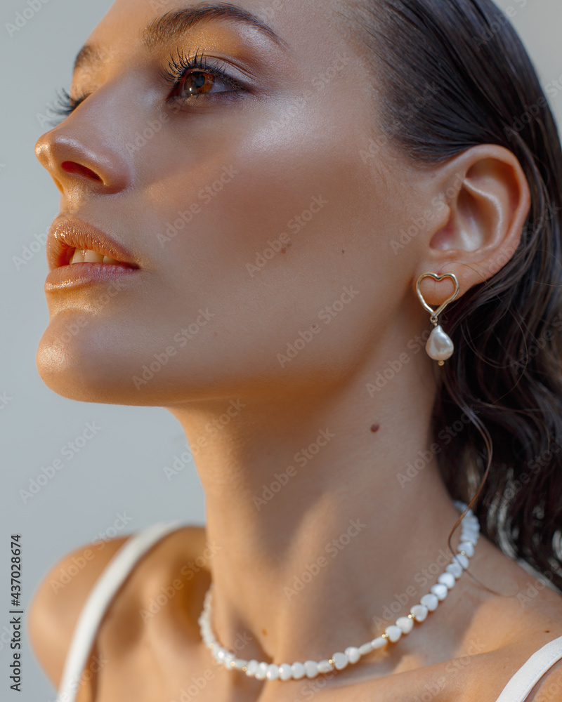 Close up portrait of beautiful woman in jewelry. Portrait of model with natural makeup and wet styling