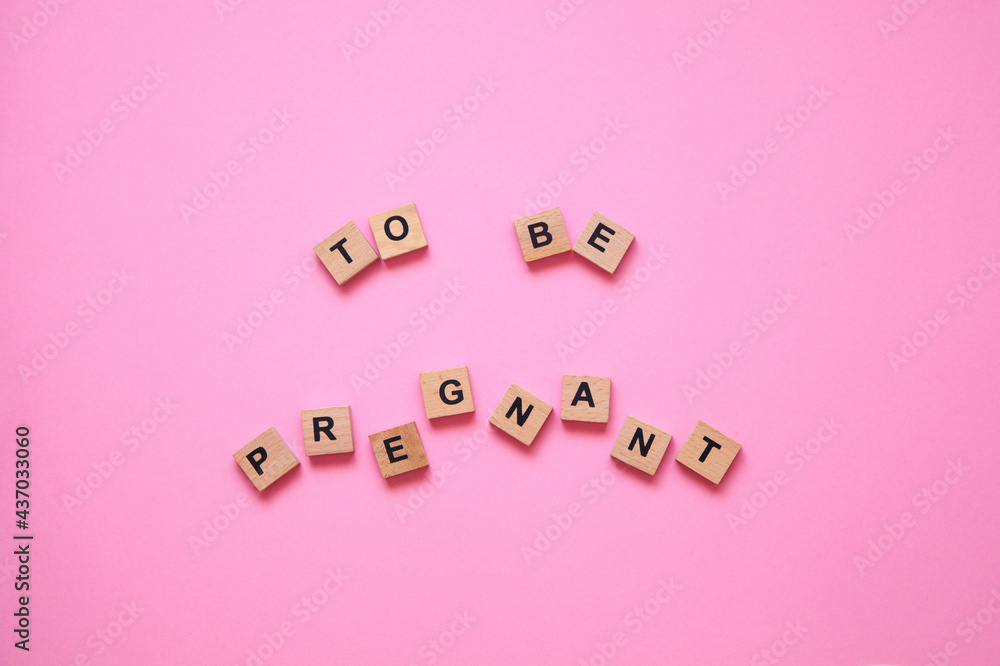 The word to be pregnant on the pink background. Women's health concept The word to be pregnant on the pink background. Women's health concept