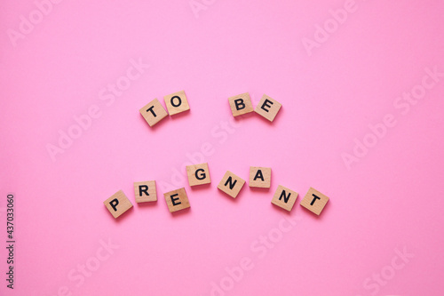 The word to be pregnant on the pink background. Women's health concept 