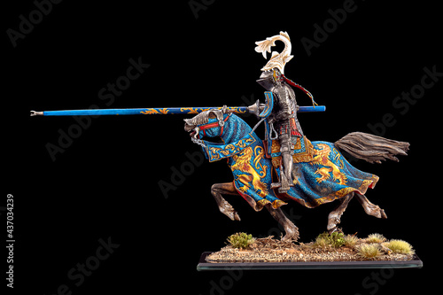 olored chess pieces in the form of people with weapons, a man on a horse in armor of blue colors, with a spear, bow and arrow on a black isolated background, warrior figurines photo