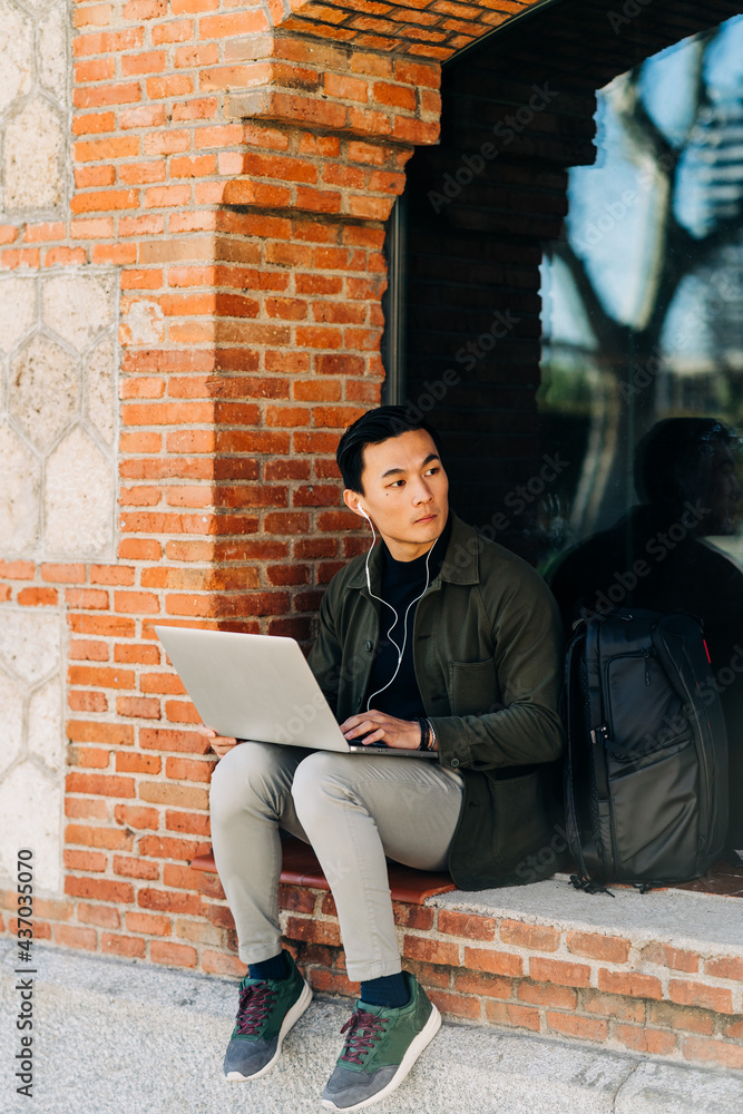 Concentrated ethnic self employed man using laptop on city street Concentrated ethnic self employed man using laptop on city street