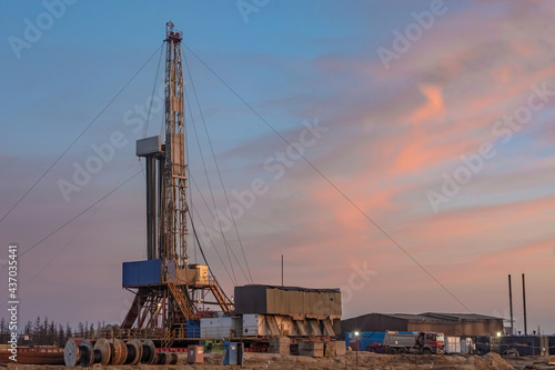 A site in the northern tundra at an oil and gas field. Drilling rig for drilling wells. Infrastructure and drilling equipment for drilling operations. Beautiful expressive sky