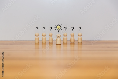 Wooden figures of people confused with question marks and an idea bulb	
