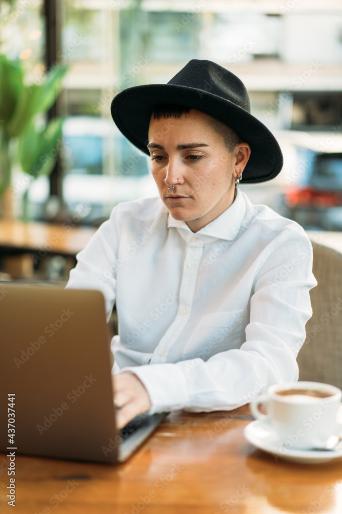 Stylish tomboy typing on laptop while working in cafe Stylish tomboy typing on laptop while working in cafe