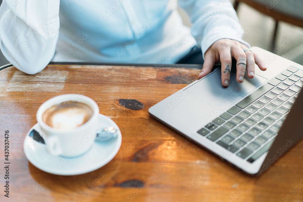 Person typing on laptop sitting at table with coffee Person typing on laptop sitting at table with coffee