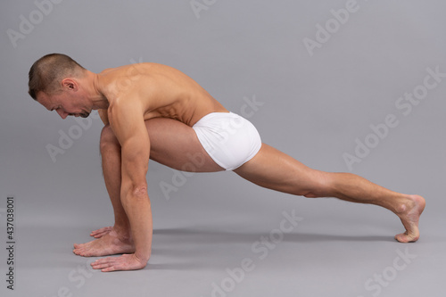 Strengthen muscles. Athletic man do lunge. Yogi man grey background. Stretching legs and arms