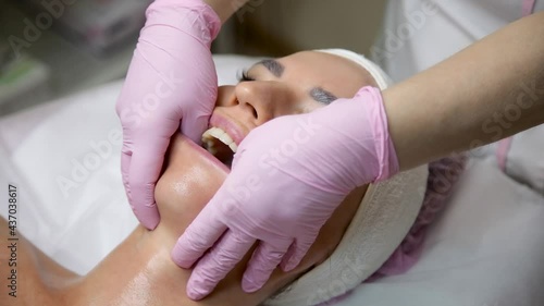 The salon specialist makes the girl a cheek massage of the face in the mouth. Buccal massage photo