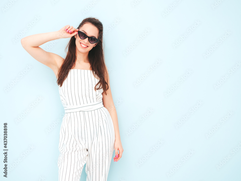 Young beautiful smiling female in trendy summer hipster clothes. Sexy carefree woman posing near light blue wall in studio. Positive model having fun indoors. Cheerful and happy Young beautiful smiling female in trendy summer hipster clothes. Sexy carefree woman posing near light blue wall in studio. Positive model having fun indoors. Cheerful and happy