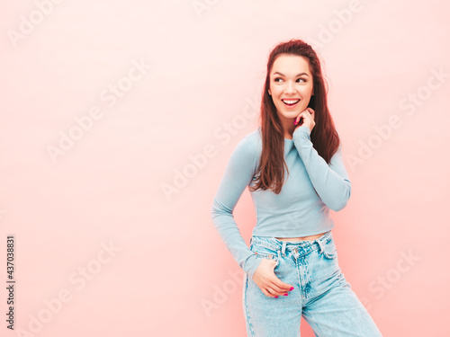 Young beautiful smiling female in trendy summer hipster clothes. Sexy carefree woman posing near light blue wall in studio. Positive model having fun indoors. Cheerful and happy