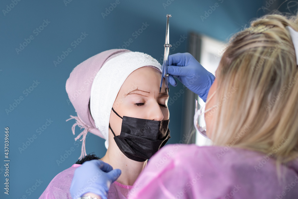 Cosmetologist measures the proportions of the eyebrows with the ruler ...