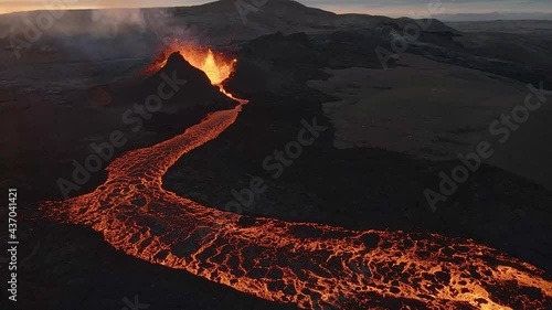 Crater of erupting volcano and lava river with sunset in background, Iceland. Aerial orbit photo