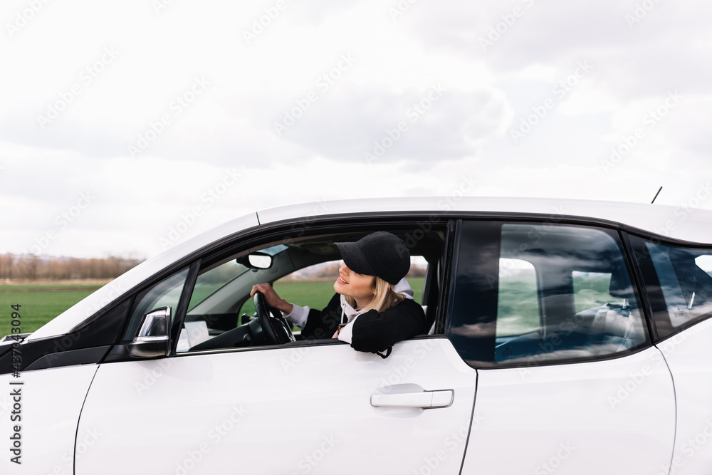 Smiling driver-woman is reflected in mirror of car.