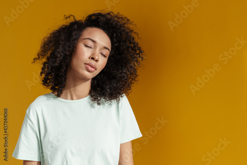 Young african woman wearing t-shirt posing with eyes closed © Drobot Dean
