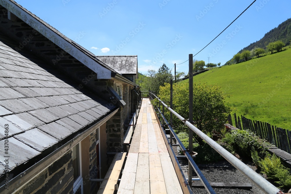 A view along scaffolding on the edge of a house in Wales, UK.