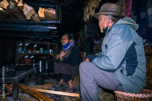 apatani tribal couple at their home near fire place cooking food at evening from flat angle © explorewithinfo