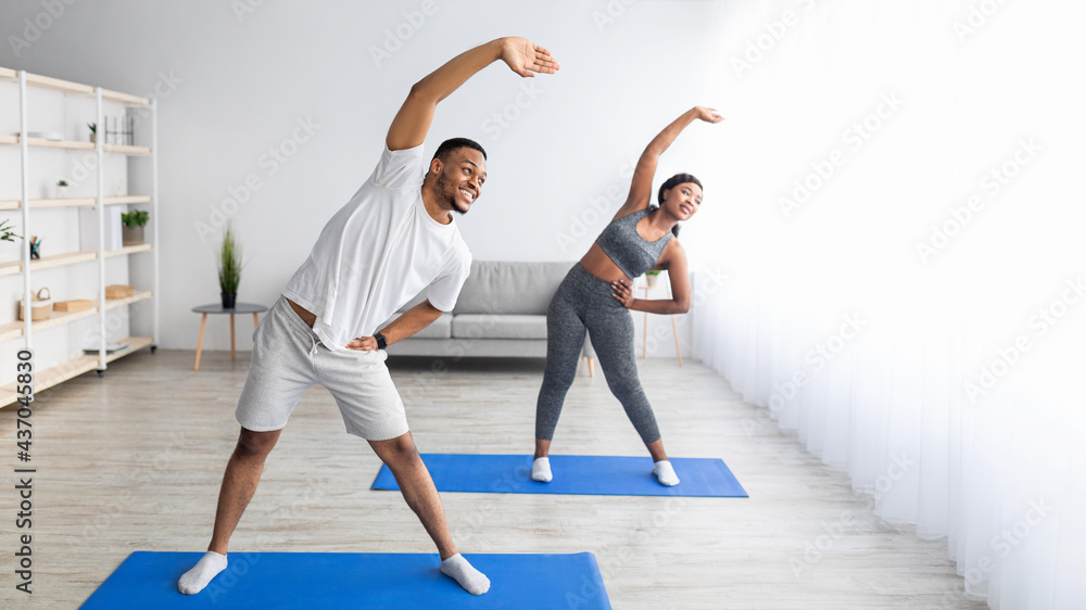 Athletic black couple bending aside, doing exercises at home, banner design with free space Athletic black couple bending aside, doing exercises at home, banner design with free space